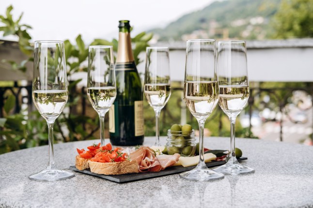 Glasses of prosecco on a table along with some bruscetta and tomatoes