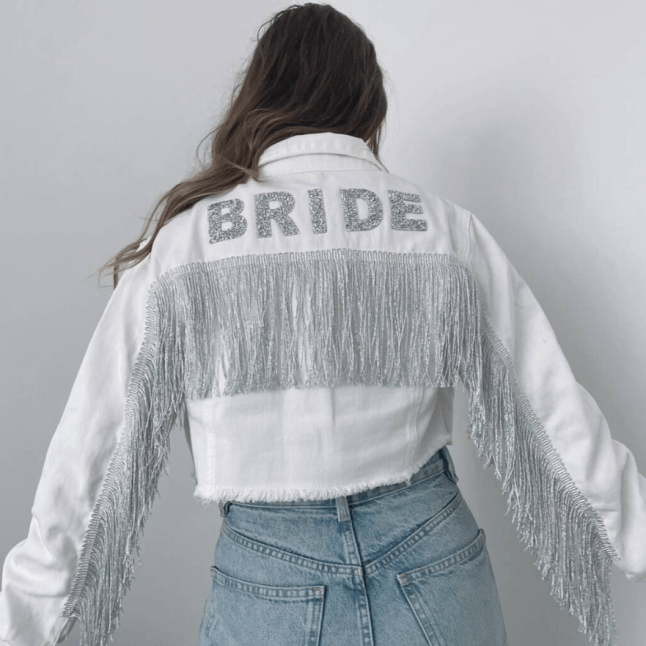 Female shows off cropped white jacket with tassles and 'Bride' detail