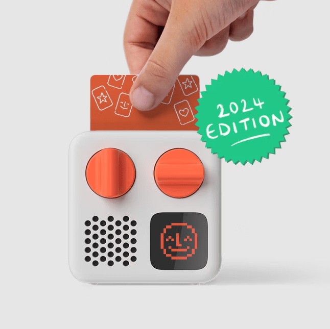 Hand pulling card from the top of grey toy with orange nobs